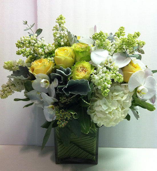 A floral arrangement of multi-colored Get Well Flowers, including roses and hydrangeas, in a white rectangular vase.